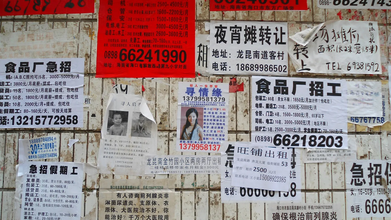 Pared cubierta de decenas de volantes pegados unos sobre otros con números de teléfono y textos de anuncios