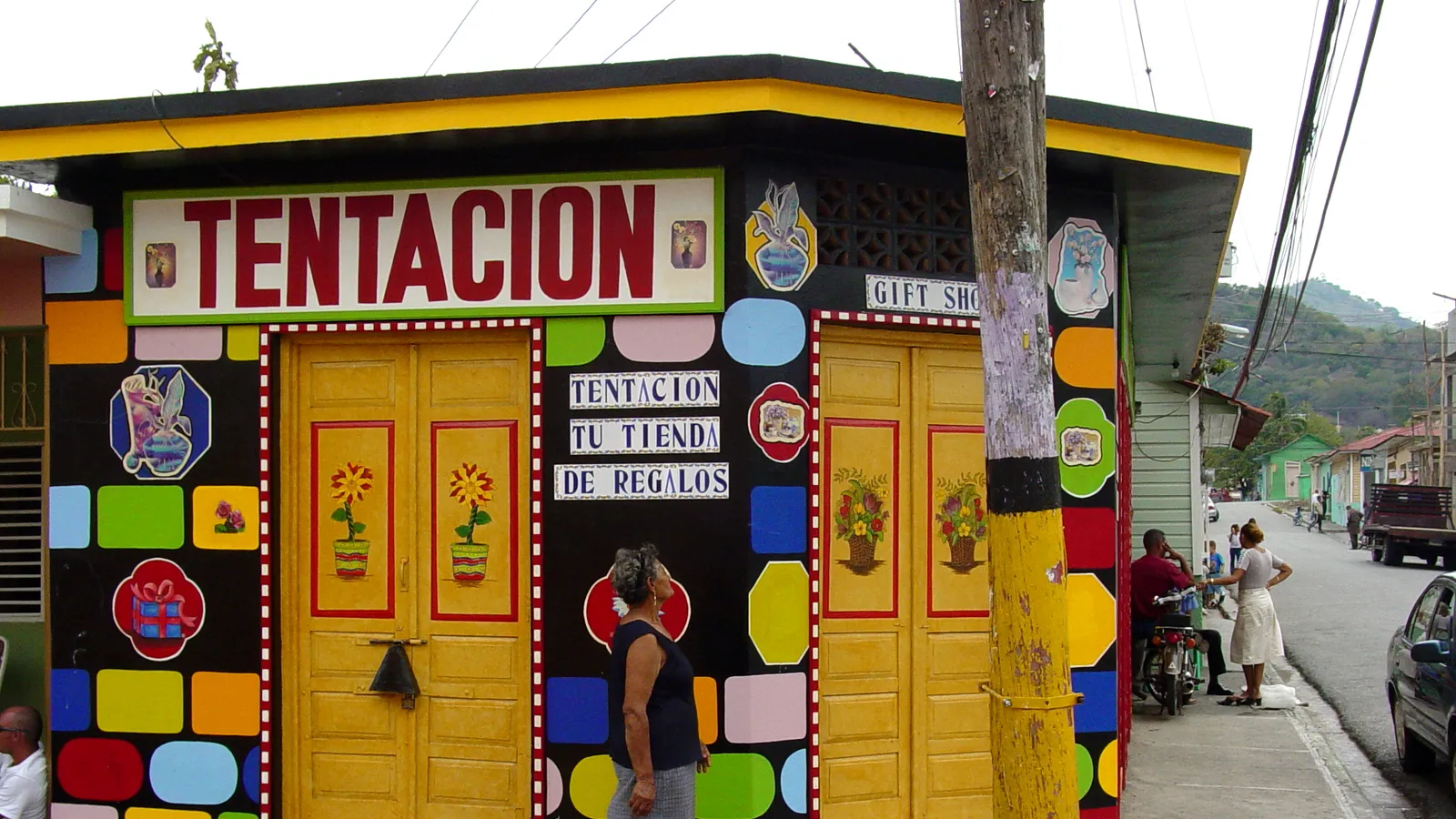 Fachada de colores de la tienda de regalos Tentación en San José de Ocoa, República Dominicana, con una mujer caminando por la acera