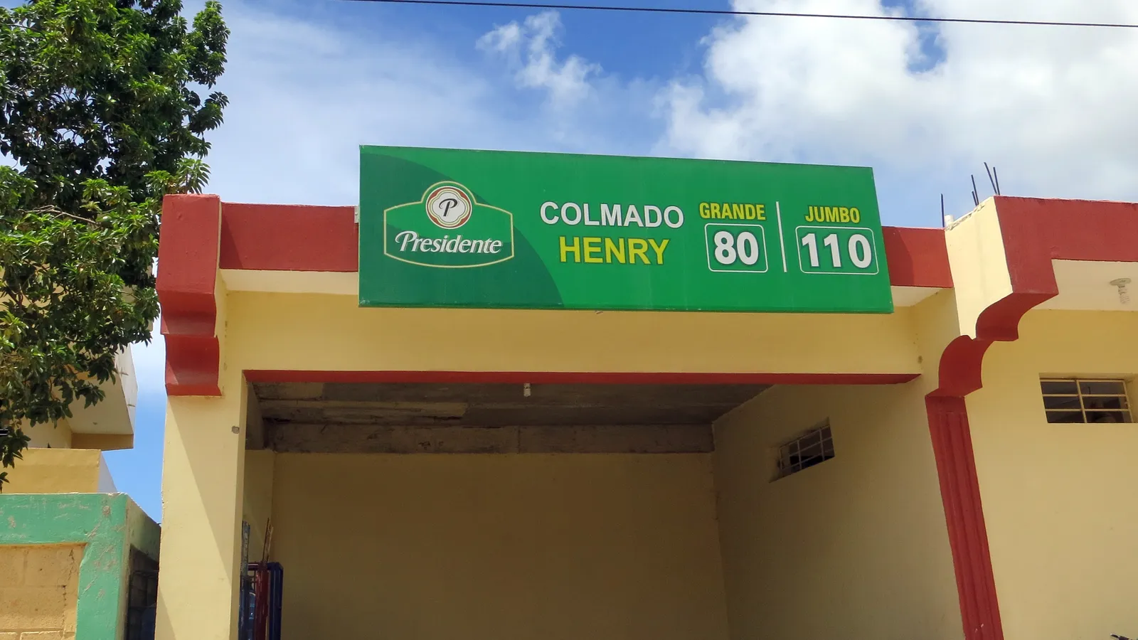 Fachada de un colmado dominicano con un letrero verde que dice Colmado Henry
